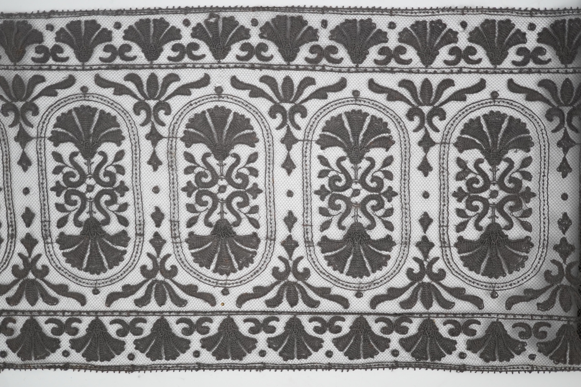 An unusual 19th century decorative length of charcoal grey machine furnishing lace, attributed to Christopher Dresser, together with a similar grey lace bonnet veil, both possibly Nottingham lace, furnishing lace 300cm j